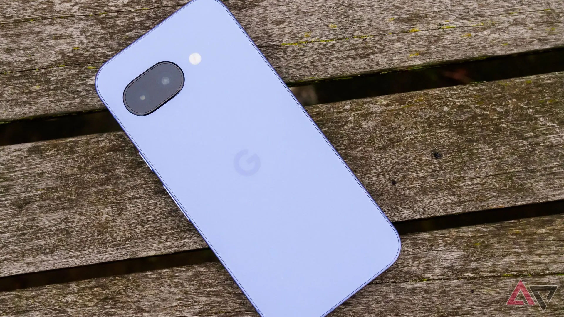 Điện thoại Google Pixel 9a đặt úp trên ghế gỗ tại công viên