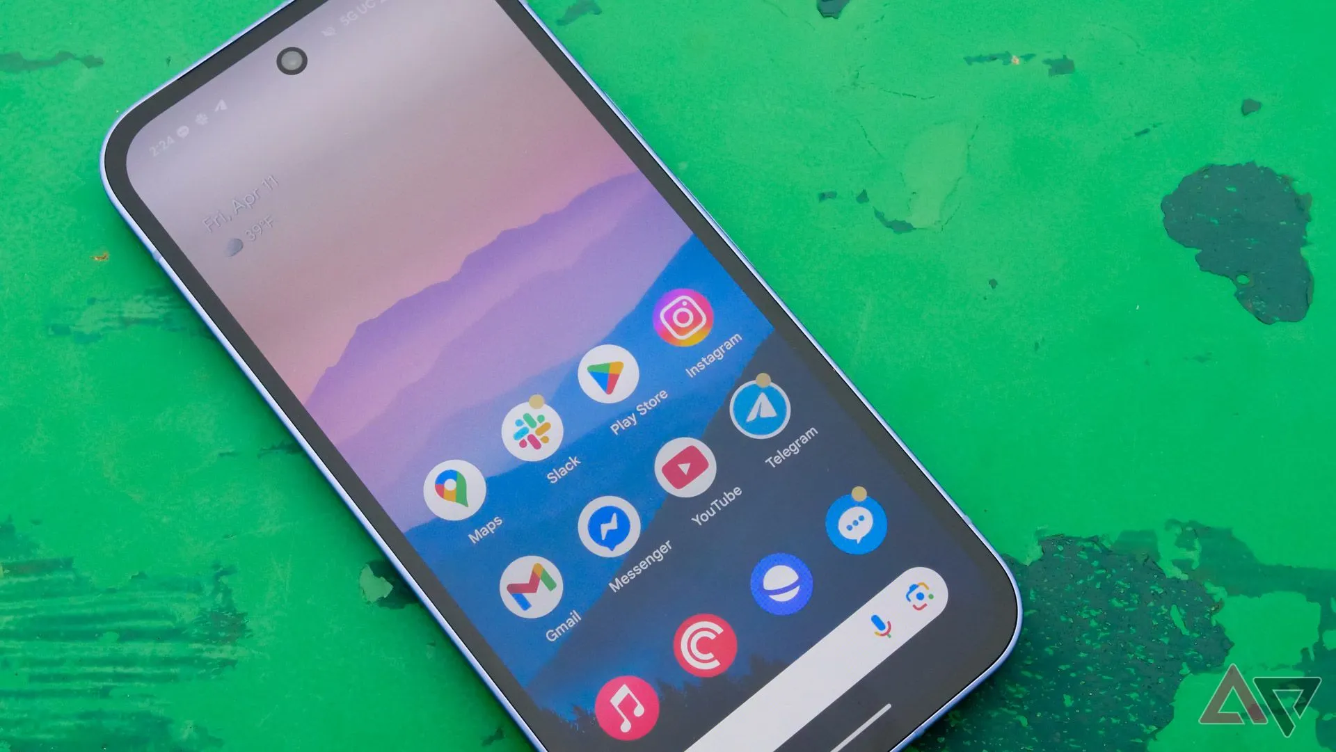 Màn hình Google Pixel 9a hiển thị ngoài trời trên bàn xanh trong công viên
