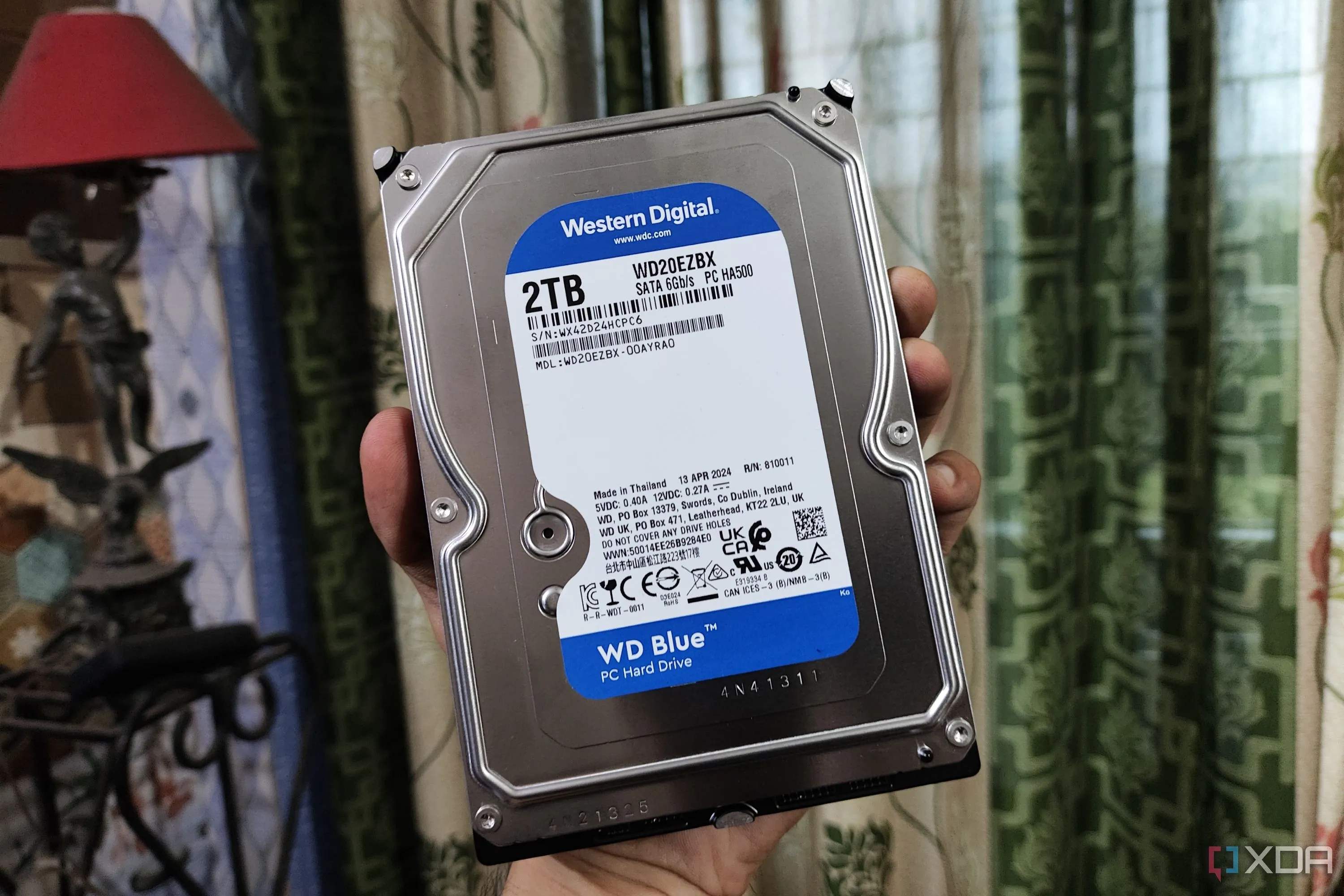 Một người đang cầm ổ cứng HDD WD Blue, biểu tượng cho việc quản lý và bảo dưỡng thiết bị lưu trữ