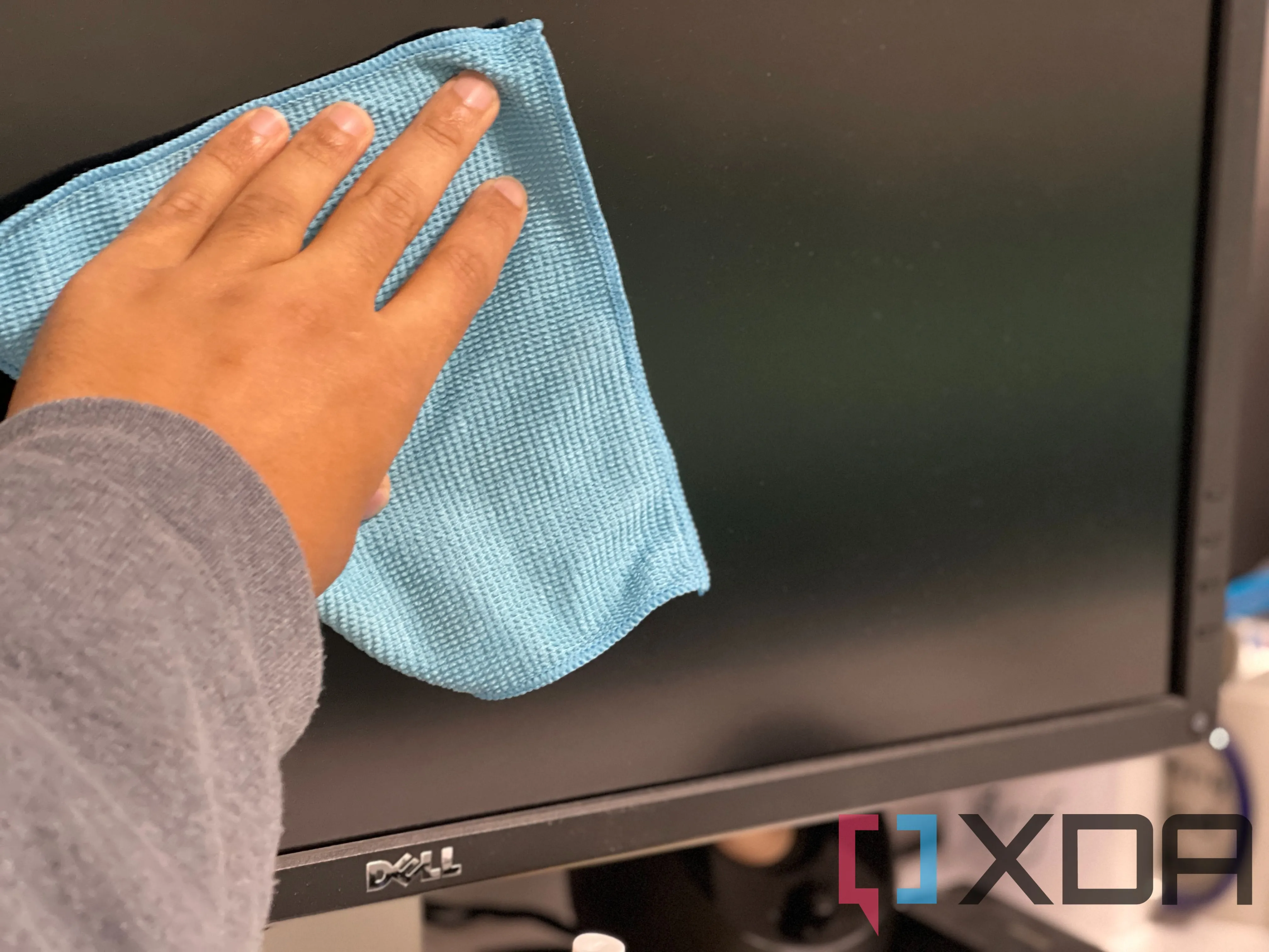 Người dùng đang cẩn thận lau chùi bề mặt màn hình OLED bằng khăn mềm, minh họa quá trình vệ sinh màn hình