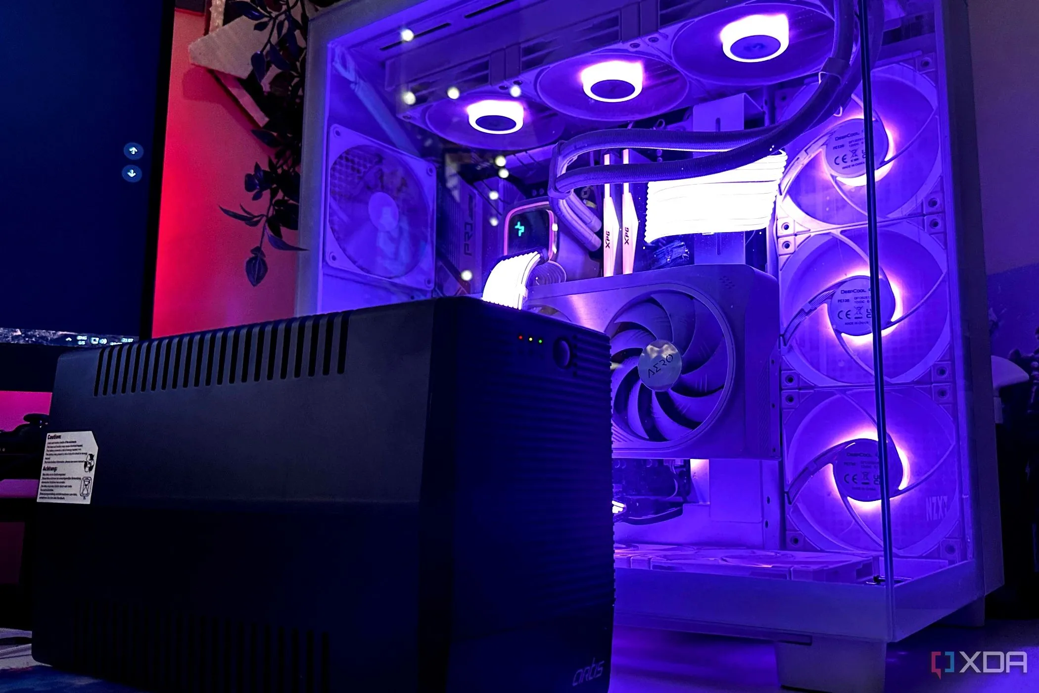 Bộ lưu điện UPS màu đen đặt cạnh thùng máy PC gaming, thiết bị quan trọng để bảo vệ hệ thống khỏi sự cố điện