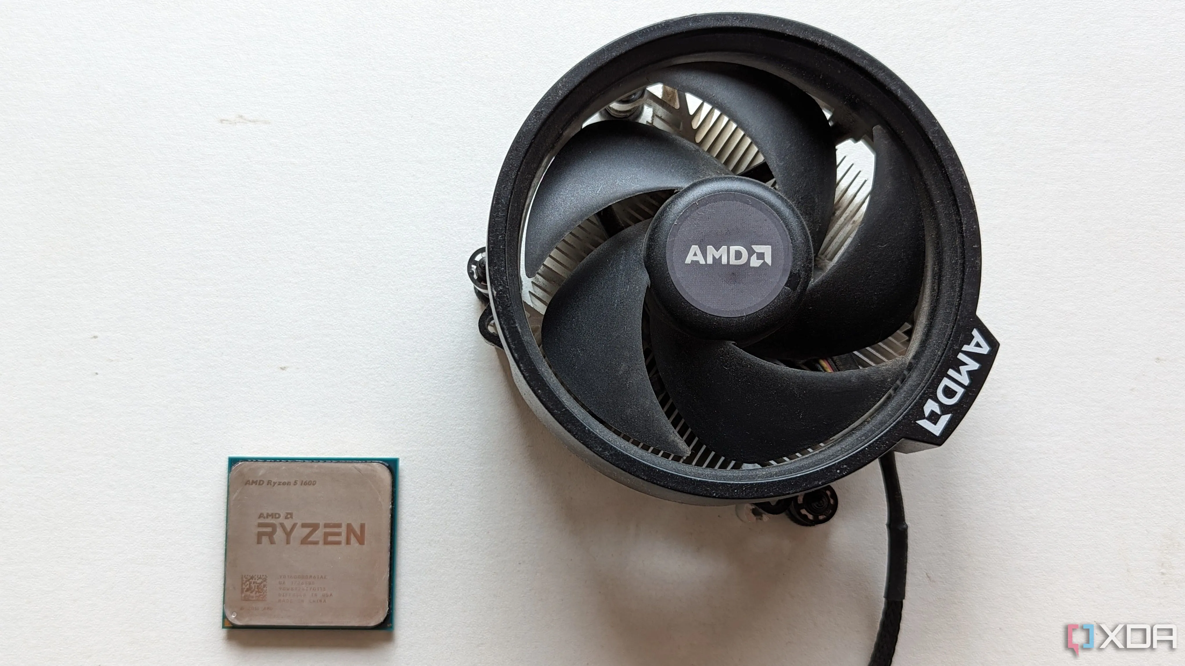 Bộ xử lý Ryzen 5 1600 và tản nhiệt gốc đặt trên bề mặt màu trắng, thể hiện CPU 4 nhân vẫn còn giá trị