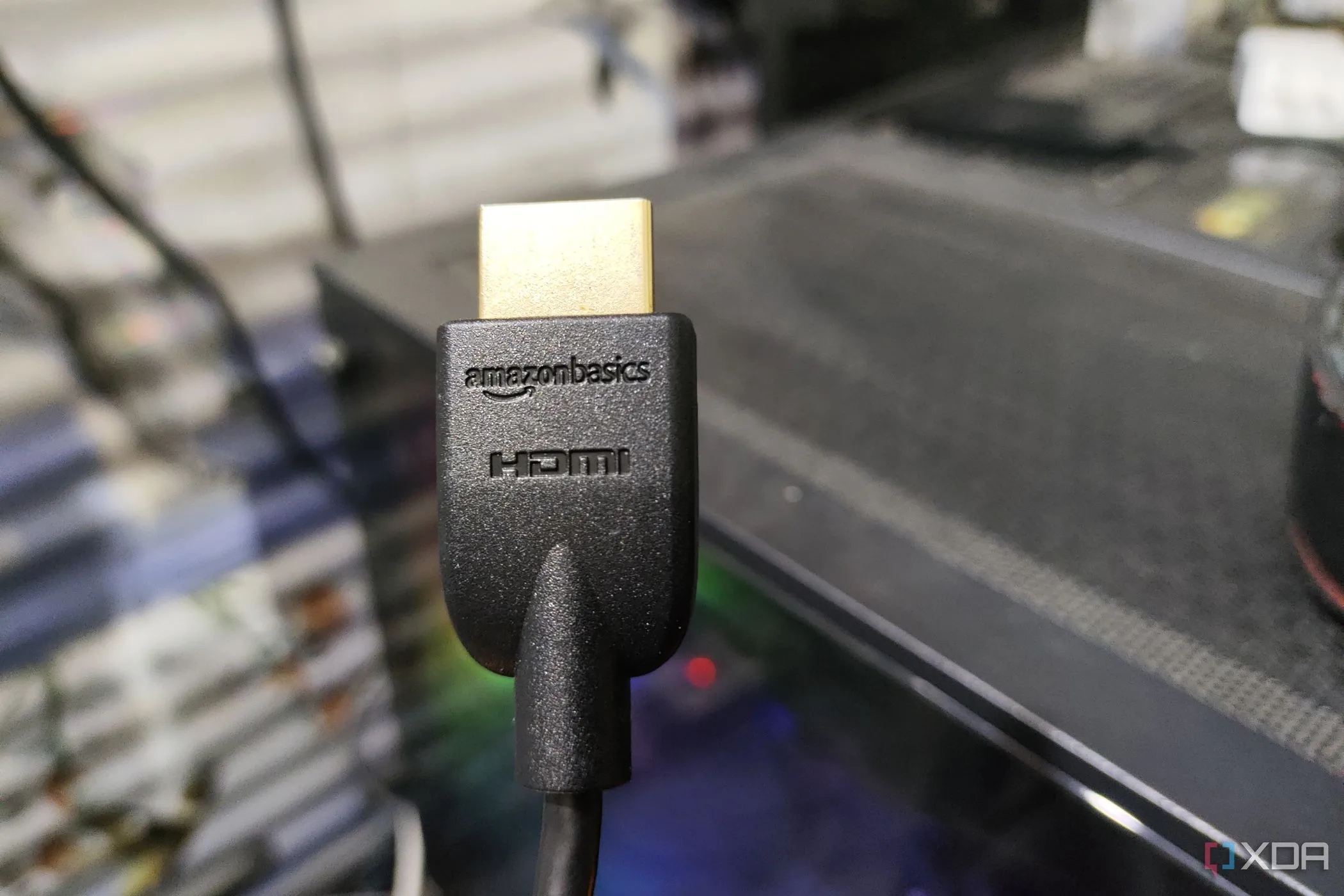 Cáp HDMI 2.1 được giữ trước một chiếc máy tính PC, thể hiện khả năng kết nối nhưng nhấn mạnh ưu thế của DisplayPort cho hiệu năng