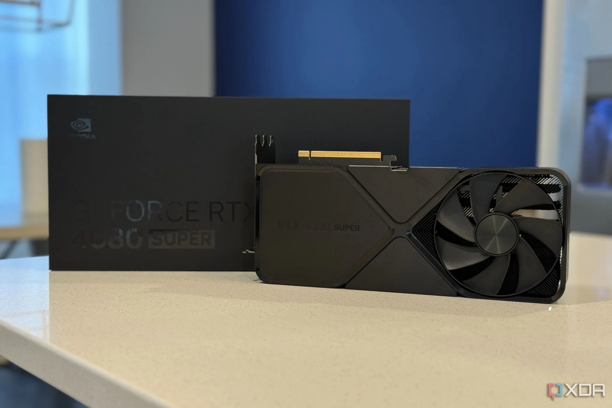 Card đồ họa Nvidia GeForce RTX 4080 Super FE đặt thẳng đứng cạnh hộp đóng gói