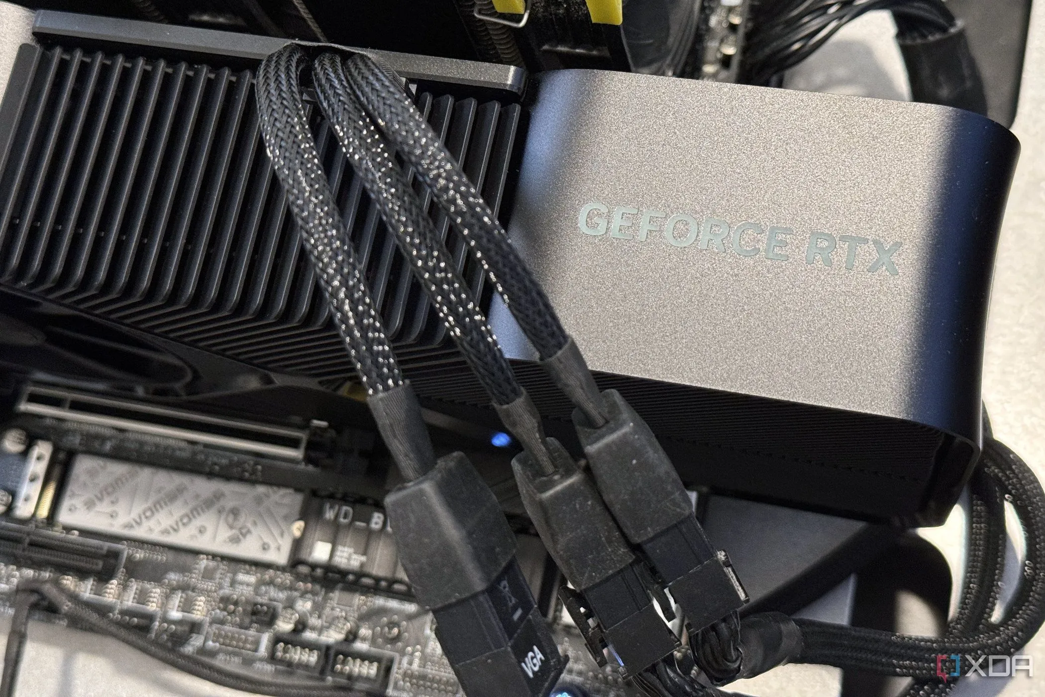 Card đồ họa NVIDIA GeForce RTX 4080 Super FE gắn trên bo mạch chủ với các cáp nguồn, đại diện cho một card đồ họa hiệu năng cao có thể ép xung