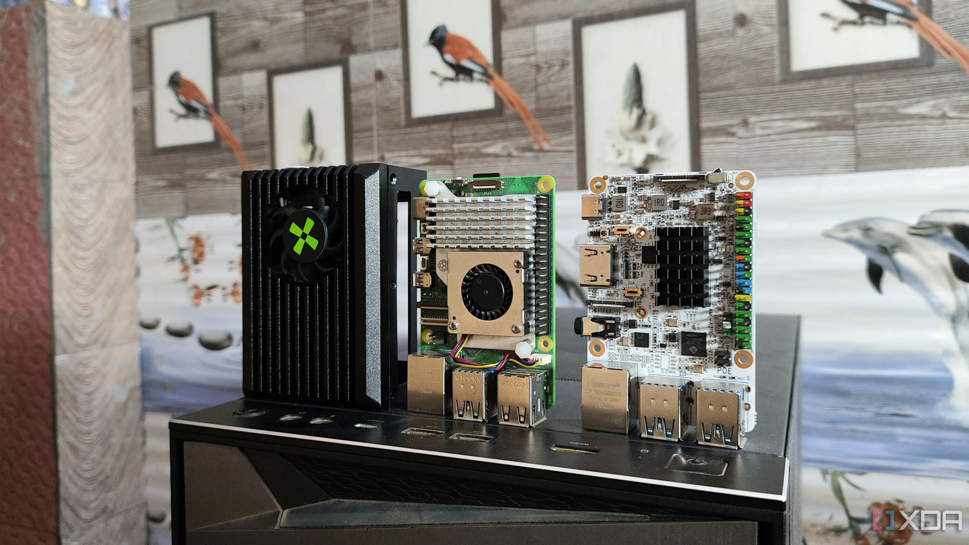 Hình ảnh các máy tính bo mạch đơn (SBCs) như Raspberry Pi 5, Radxa X4 và Libre Computer Alta SBC đặt trên một chiếc PC, minh họa các thiết bị phần cứng khiêm tốn dùng cho home lab.