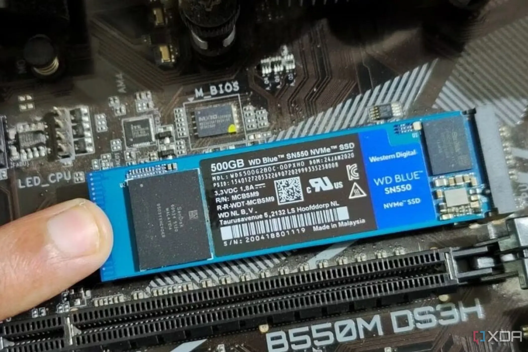 Hình ảnh một người đang giữ mô-đun SSD M.2 bằng ngón tay trên bo mạch chủ