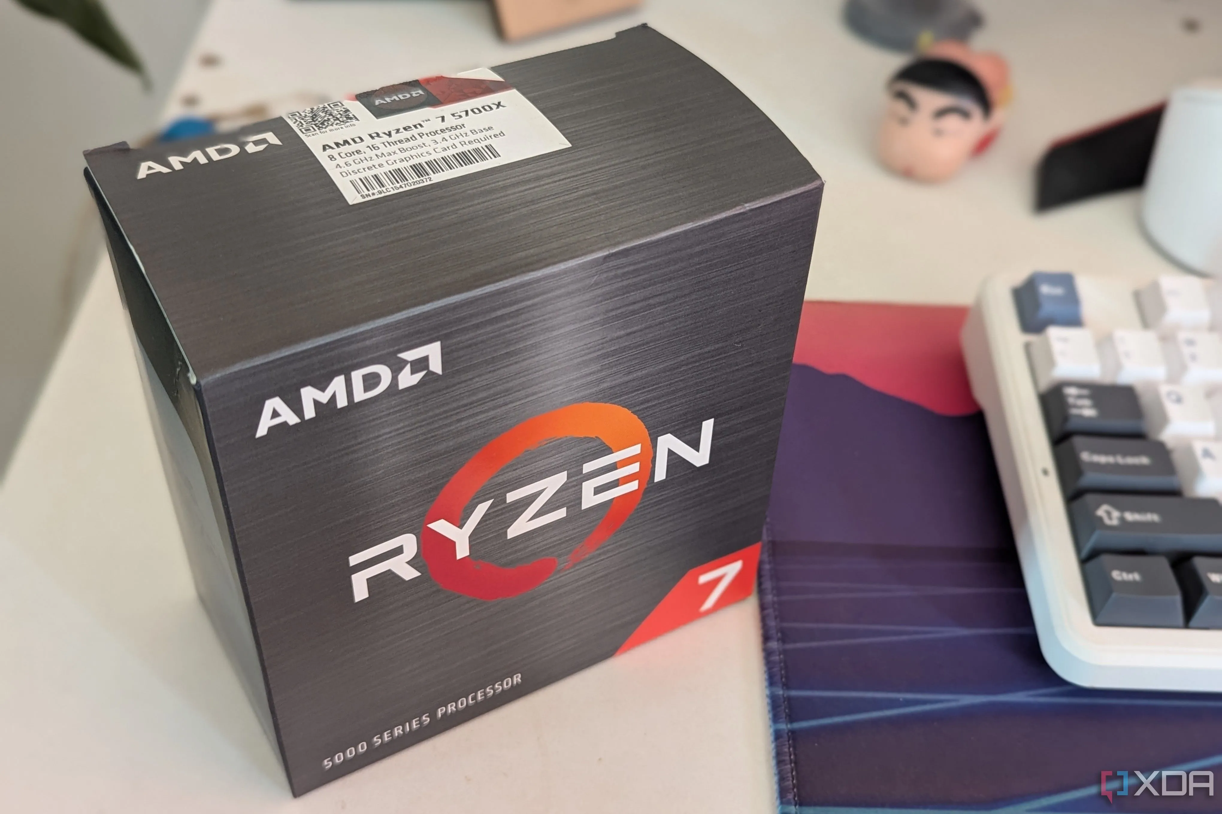 Hộp CPU AMD Ryzen 7 5700X đặt trên bàn làm việc cạnh bàn phím, minh họa cho CPU 8 nhân không cần thiết cho gaming