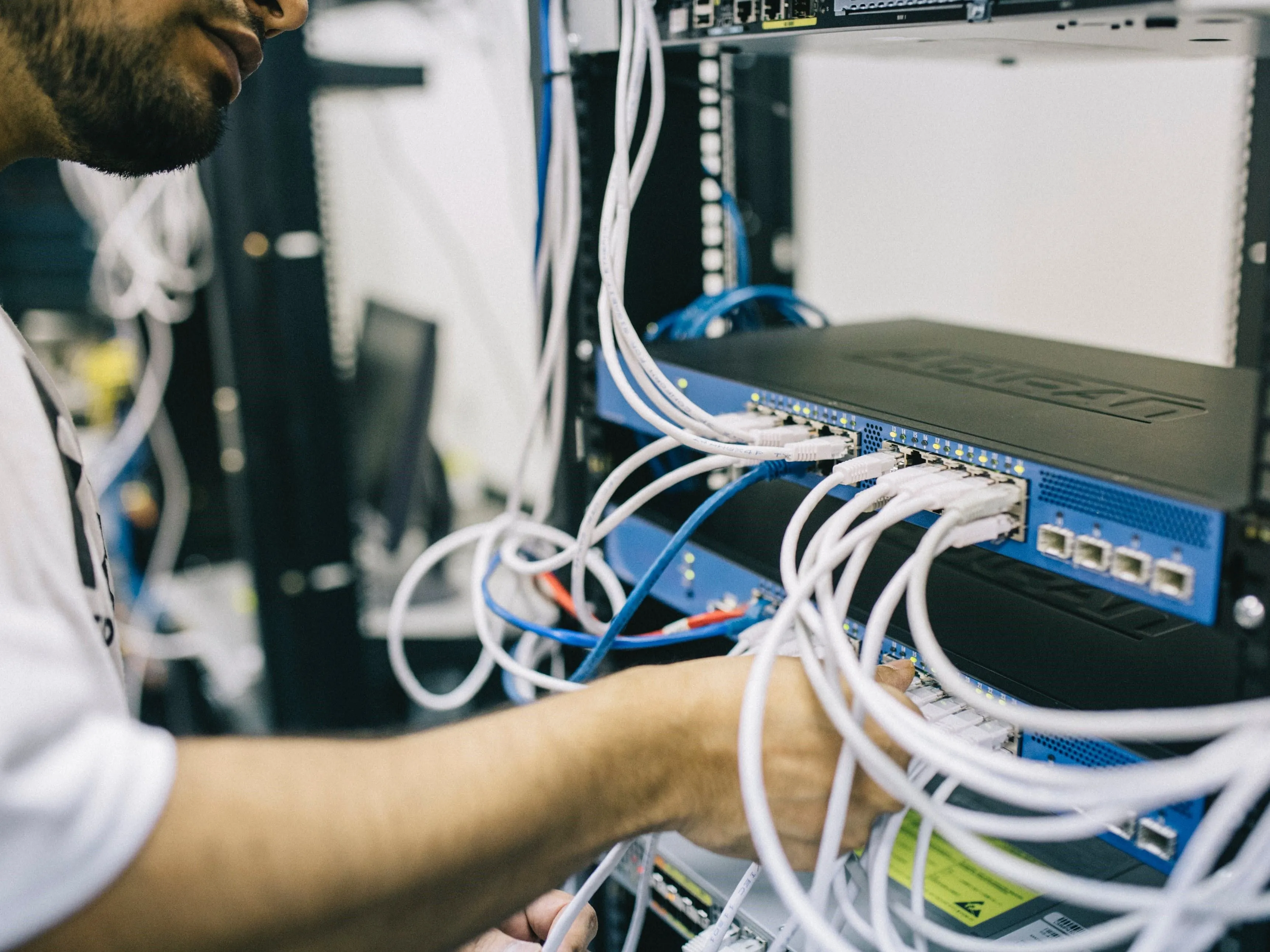 Kỹ sư đang cắm cáp Ethernet vào bộ chuyển mạch mạng, nhấn mạnh vai trò của người quản trị trong bảo mật.