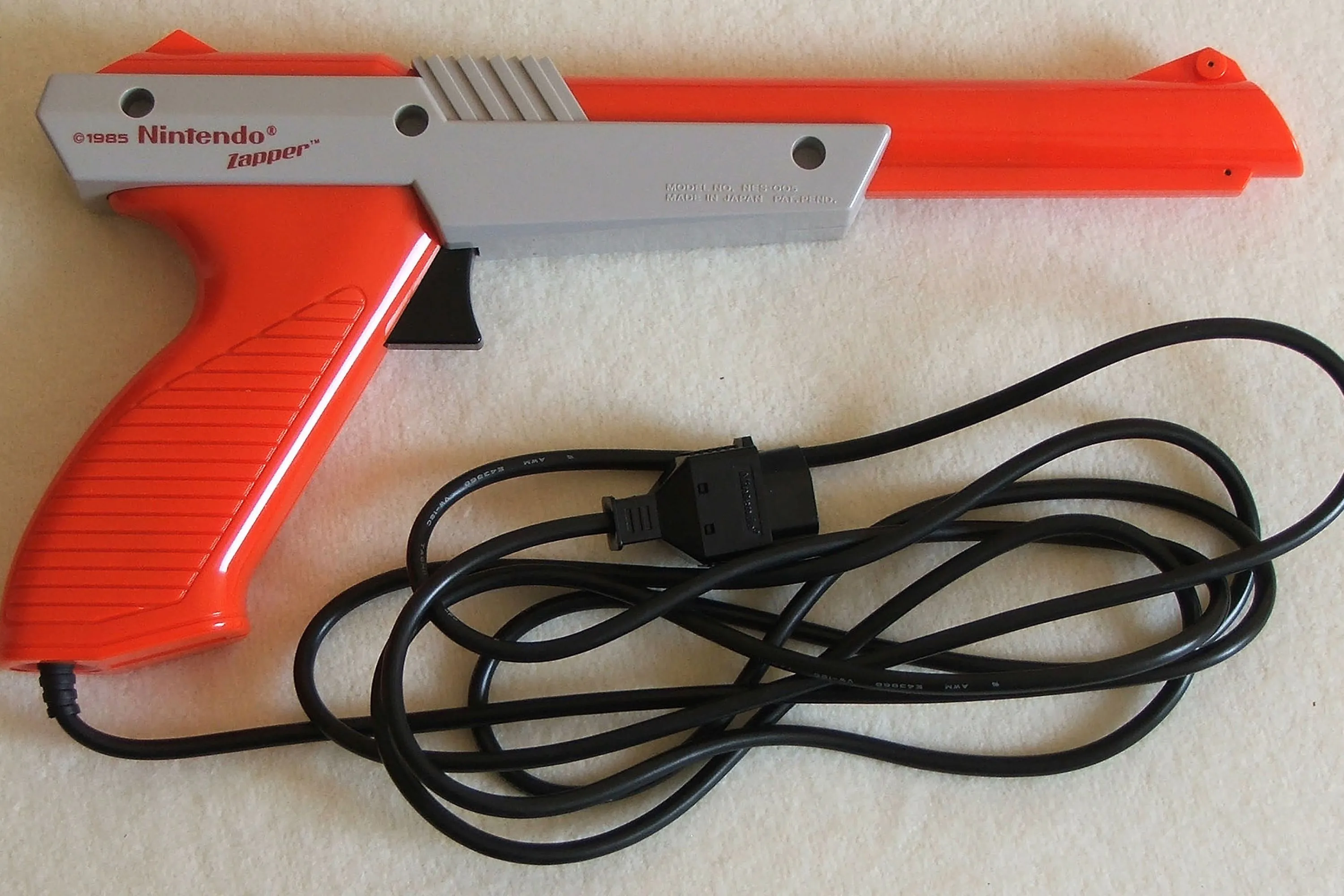Một khẩu súng NES Zapper màu xám nằm trên mặt sàn, biểu tượng của game bắn súng kinh điển Duck Hunt.