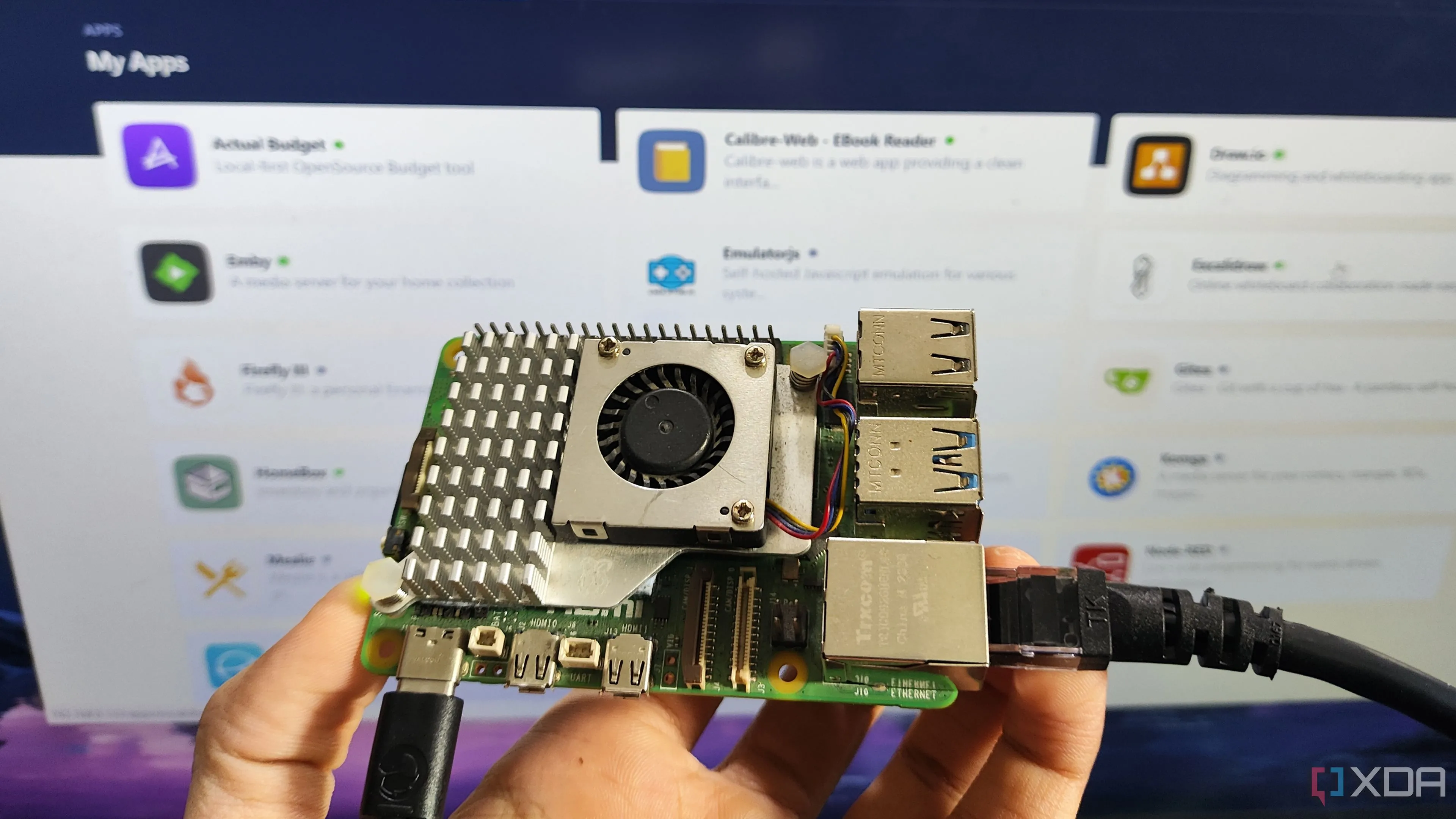 Một người cầm Raspberry Pi trước màn hình hiển thị máy chủ RunTiPi đang hoạt động