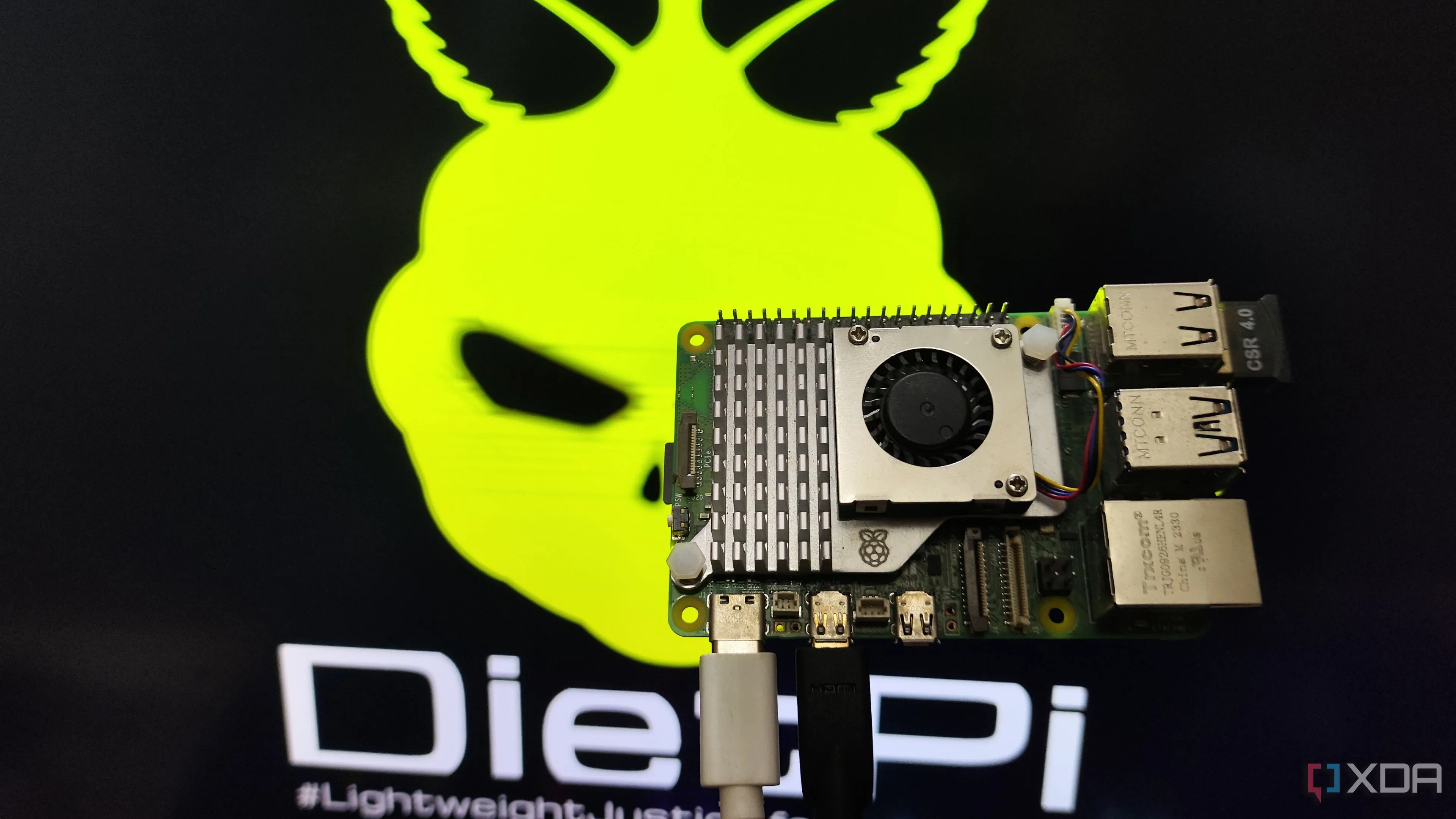 Một người đang cầm Raspberry Pi 5 trước màn hình hiển thị môi trường máy tính để bàn DietPi LXDE, minh họa khả năng chạy trên các máy tính bo mạch đơn cấu hình yếu.