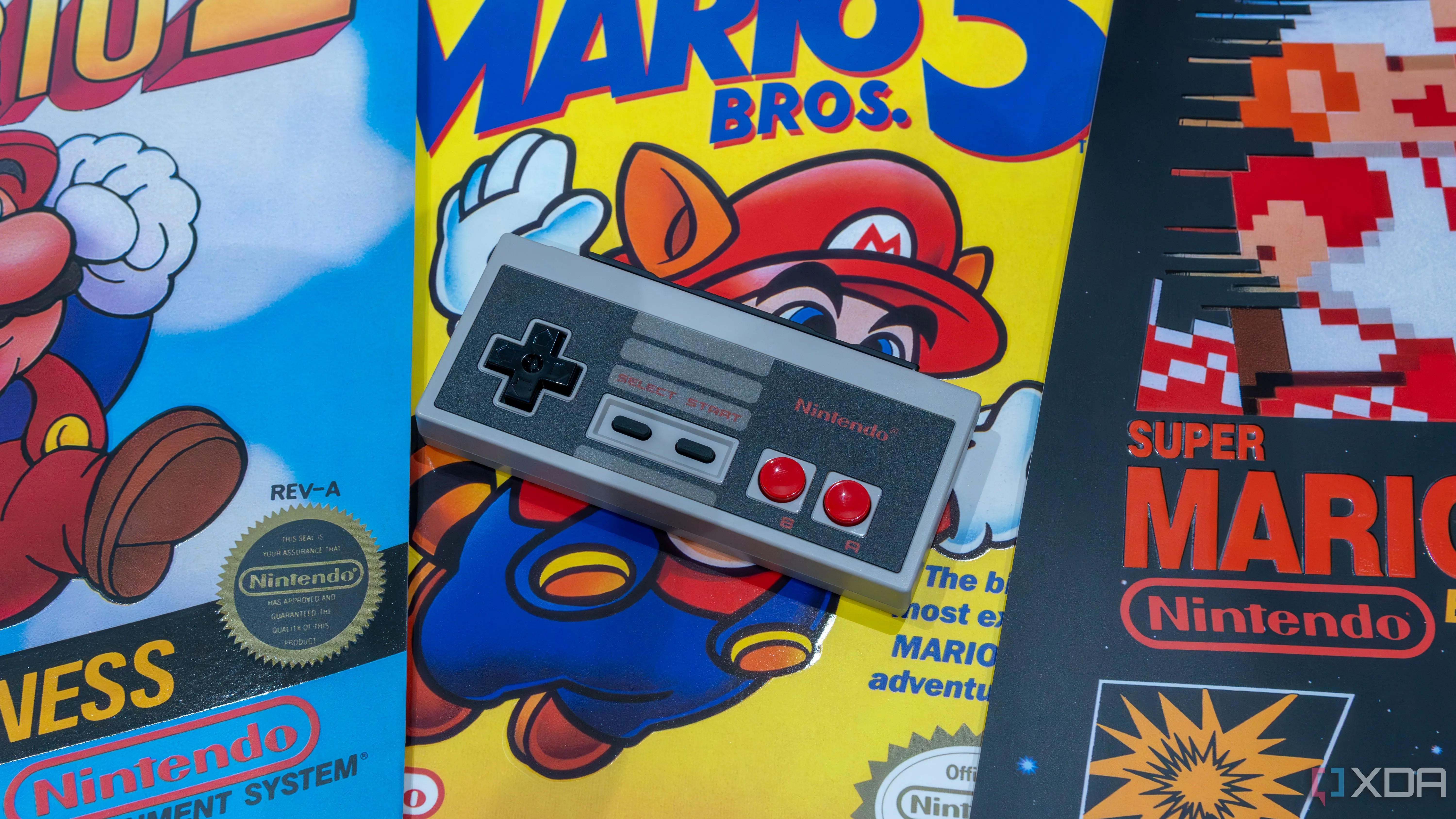 Tay cầm NES replica cho Nintendo Switch đặt trên các poster game Mario khác nhau, gợi nhớ game NES cổ điển